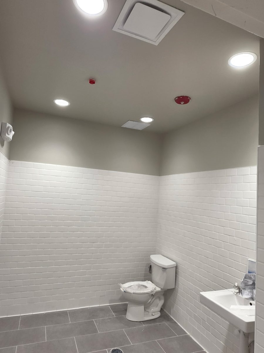 Completed restroom with white subway tile wainscot and tile floor